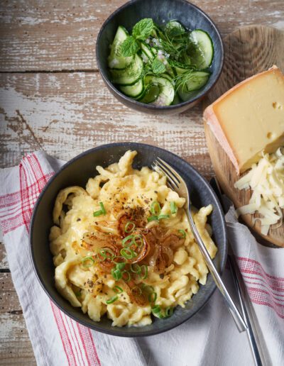 handgemachte Allgäuer Käsespätzle mit Röstzwiebeln und kleiner hausgemachter Gurkensalat, vegetarisch, frisch, soulfood, regional, catering